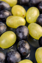Obraz premium ripe grapes of blue and green color lying on a bowl, covered with drops of water, wet fruits of pure green and blue grapes during cooking