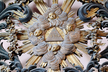 Bayeux cathedral. Gilded rococo sunburst with Hebrew Tetragrammaton in a radiant triangle, surrounded by clouds and cherub heads. Bayeux.  France.