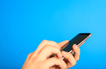 Close-up of a hand holding a smartphone against a vibrant blue background, symbolizing mobile technology, communication, and connection. Perfect