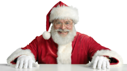 Friendly santa claus with a white beard and red suit smiling and leaning forward on a white surface isolated on transparent background