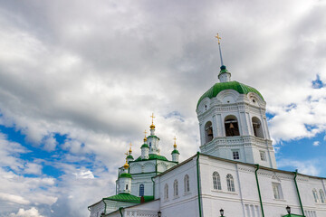 View from below in white belfry with bells of the of the Epiphany Cathedral against blue sky with grey clouds background at Yeniseysk in Krasnoyarsk krai, Russia.