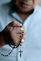 Man praying the rosary.  Hail Mary, full of grace. Close-up of the crucifix.