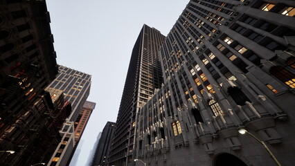 Obraz premium Tall buildings reach for the sky as city lights begin to glow at dusk. The blend of modern and historical architecture creates a stunning skyline, showcasing urban life.