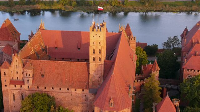 Castle of the Teutonic Order in Malbork by the Nogat river at sunset. Poland