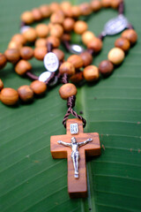 Wooden rosary on a banana leaf. Praying in nature concept.