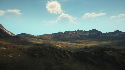 Lush green valleys stretch beneath rugged mountain peaks, where sunlight dances across the terrain. Above, a serene blue sky features delicate white clouds softly drifting.