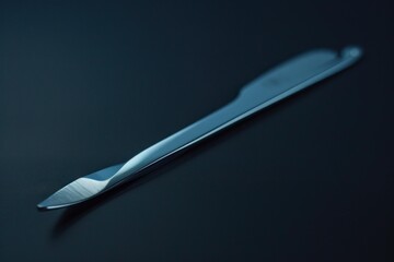 Sleek metallic scalpel rests on a dark reflective surface, showcasing its sharp precision and modern design