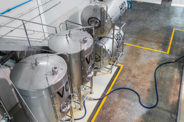 Modern brewery interior showing stainless steel tanks, vats, and industrial equipment for beer production