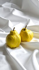 Two yellow quinces on white fabric