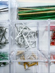 Assorted electrical components and jumper wires sorted in transparent plastic organizer, top-down macro view
