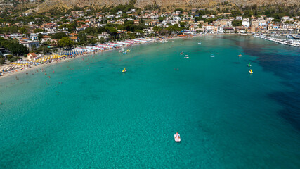 Aerial view of Mondello Bay, located near Palermo, Sicily, Italy. There are many boats on holiday in the gulf. The Mediterranean Sea is azure and crystal clear.