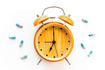 Medical treatment pills and vintage alarm clock, top view. Time to take medicine concept