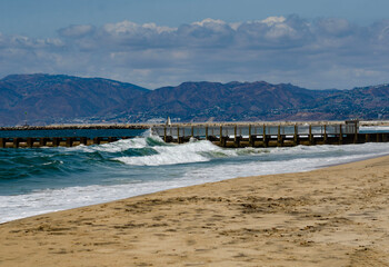 Obraz premium Los Angeles, California, sandy ocean shore, pier on the horizon, waves crashing onto the beach