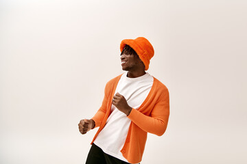 Handsome young man in vibrant orange attire showcasing fashionable style with a joyful expression