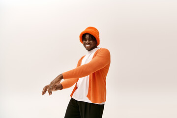 Handsome young man wearing stylish attire poses confidently in bright orange outfit