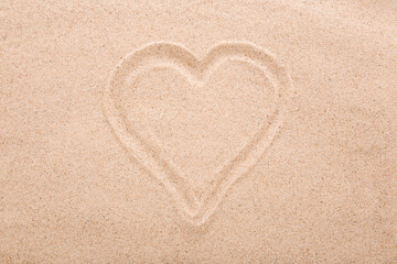 Drawn heart shape on dry light brown sea sand background. Closeup. Love concept. Closeup. Top down view.