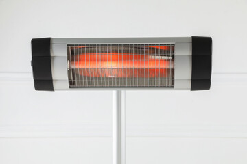 Electric infrared heater near white wall indoors, closeup
