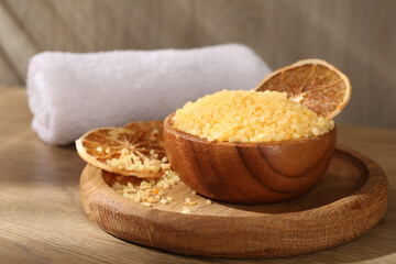 Natural sea salt with dried orange slices and towel on wooden table, closeup