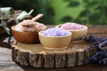 Different types of sea salt on wooden table against blurred background, closeup