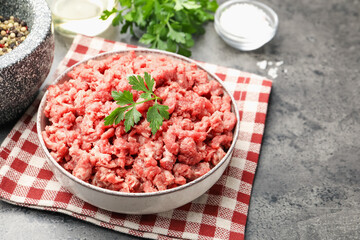 Raw minced meat with parsley and spices on grey table, closeup