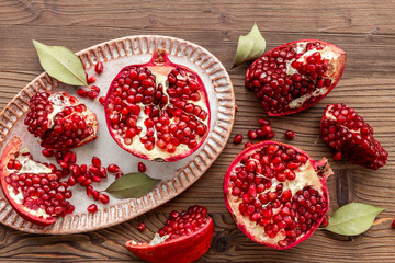 Plate full of fresh ripe pomegranate with cut in half and pieces, top view.