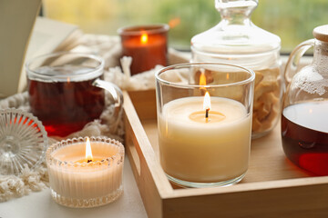 Burning candles and tea on windowsill on rainy day, closeup. Autumn atmosphere