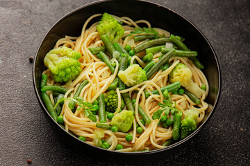 Spaghetti vegetables green peas, broccoli, string beans, kohlrabi vegetarian pasta tasty snack fresh delicious gourmet food background on the table rustic top view copy space vegan food