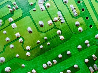 Close-up of green printed circuit board with solder joints and copper traces, macro view of electronic component