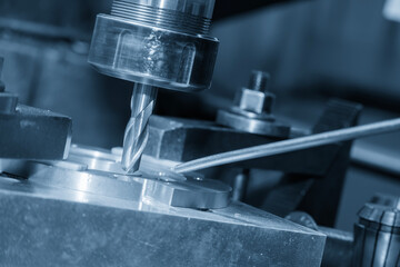 The hole drilling process the brass material parts on NC milling machine by drill tools in the light blue scene.