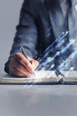 Businessman writing growth plans in notebook with rising arrows