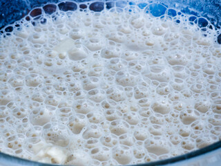 Frothy white bubbles form a dense, intricate pattern on a liquid surface, close up texture evoking freshness, cleansing or fermentation with delicate, airy detail