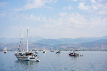 Fototapeta premium Scenic marina in Fethie, Turkey with wooden sailing boats and hills under clear blue sky 