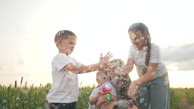 Children and family laugh under the summer sun, chasing shiny bubbles happily. The bubble toy makes bubbles rise, faces shine bright. Summer, family, children, bubbles, joy, fun, smiles, outdoor.