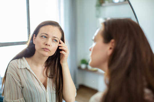 Young woman examining skin in mirror