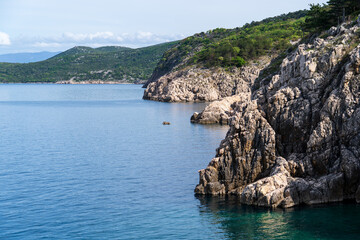 KRK Island, Vrbnik, Croatia - April 19, 2025: Cityscape. View of the coastline, rocky beach, and mountains