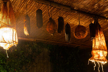 A moody and atmospheric night scene from a medieval tavern or inn. The focus is on traditional cured food, illuminated by handmade lamps. Ample copy space below.