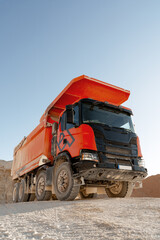 Construction dump truck on sandy terrain under blue sky
