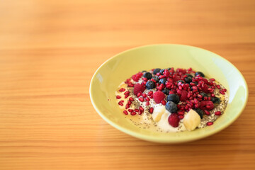 Homemade yoghurt with fresh berries and chia seeds in plate on a wooden table