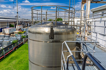 A large stainless steel tank with an industrial building