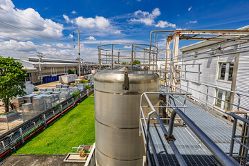 A large stainless steel tank with an industrial building