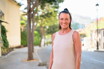 Portrait of a smiling mature Scandinavian tourist woman walking in the street in Spain