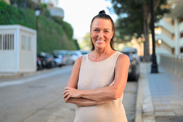 Portrait of a beautiful mature Scandinavian woman smiling with arms crossed in the street