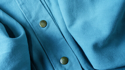 Blue denim fabric texture with metal snap buttons. Close-up buttons jacket. Concept of weave,...