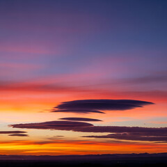 Fototapeta premium An ethereal twilight spectacle unfolds as vibrant hues paint the expansive sky, illuminating distinct cloud formations in a breathtaking evening panorama