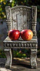 Two apples sit on a small, ornate, gray chair outdoors
