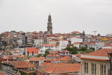 Fototapeta premium Panoramic view of Porto with red-tiled roofs, historic bell tower, and construction crane. Architectural contrast, urban texture, cultural ambiance.