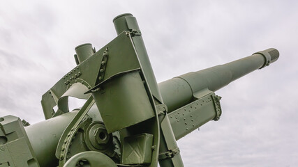 The barrel of a large-caliber cannon is aimed at the gloomy sky. Soviet and Russian artillery. A weapon for long-range strikes. Armed conflicts and wars.