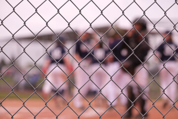 Blurry and soft focus baseball players photographed through a chain link fence