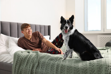 Pet friendly hotel. Man and his cute dog on bed indoors