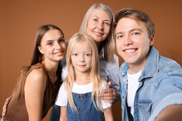 Fototapeta premium Man taking selfie with his mom and family on brown background
